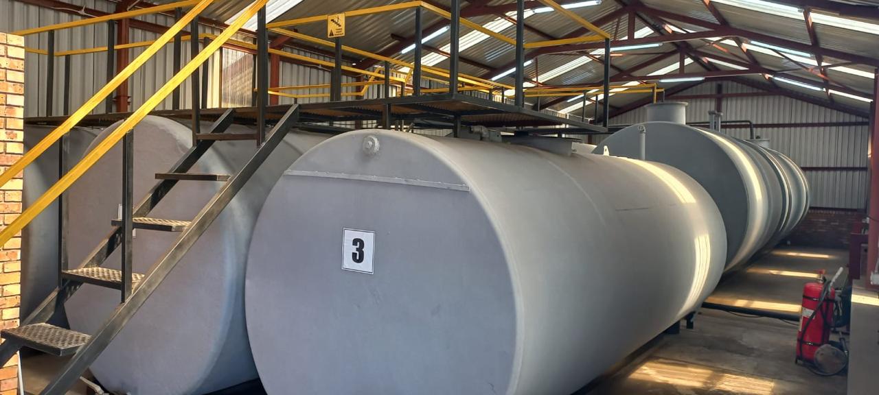 Row of large fuel storage tanks inside a shed